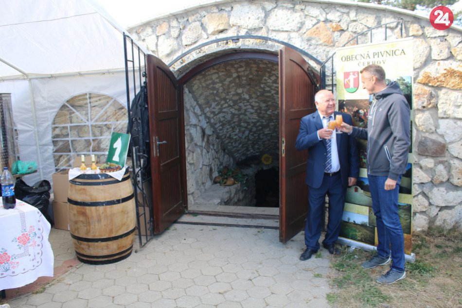 Dvaja muži si pripíjajú burčiakom pri vstupe do vinárskej pivnice